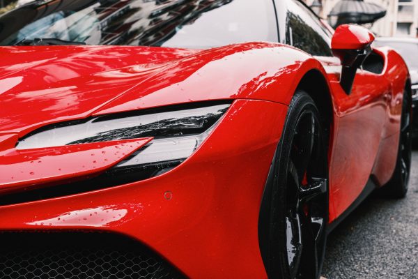 Detailed view of a shiny red luxury sports car exterior showcasing its sleek design and reflections. Voitures 4K