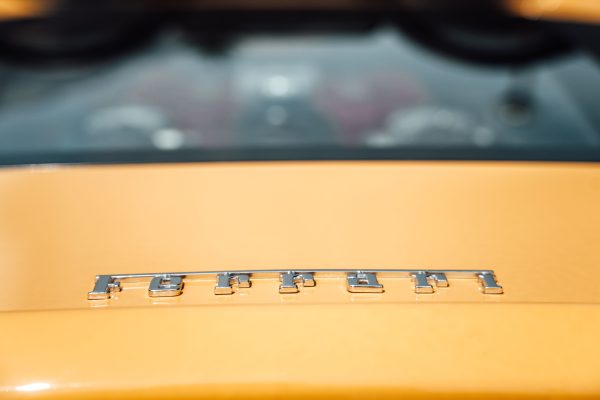 Detailed view of a yellow Ferrari emblem on a luxury sports car. Voitures 4K