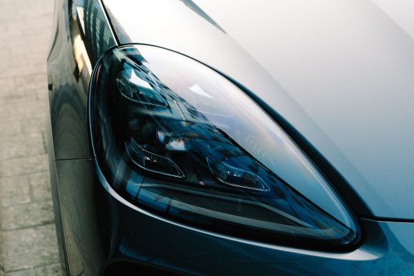 Detailed view of sleek car headlight reflecting urban surroundings. Voitures 4K
