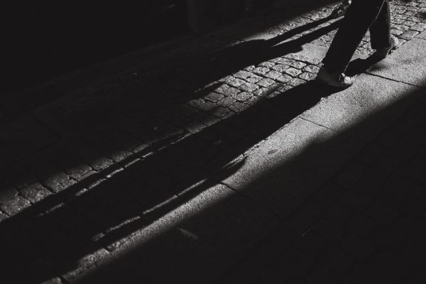 Dramatic black and white photo capturing shadows on a textured cobblestone street. Dark 4K