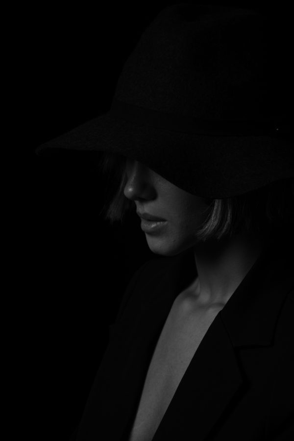 Dramatic black and white portrait of a woman in a hat, emphasizing shadows and elegance. Mobile 4K