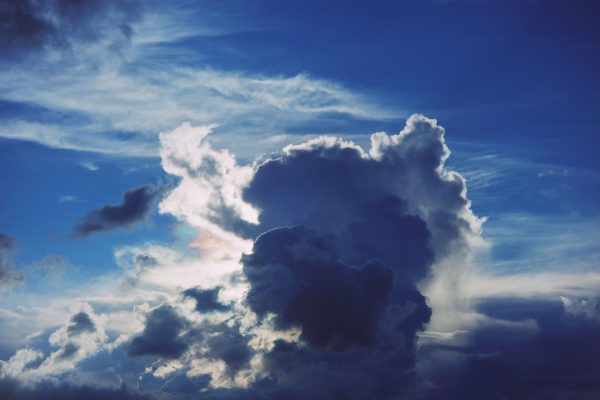 Dramatic cloudscape with vibrant blue sky and sunlight breaking through, showcasing dynamic weather patterns. Dark 4K