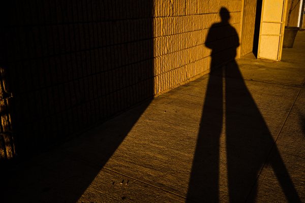 Dramatic long shadow of a person on an urban sidewalk during sunset, creating a mysterious mood. Dark 4K