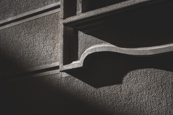 Dramatic shadows on a textured concrete wall create urban contrast. Dark 4K