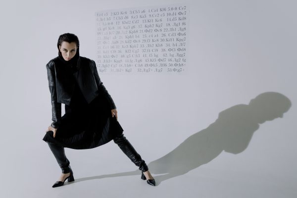 Dramatic studio portrait of a woman in fashion-forward attire, casting a shadow. Charme 4K