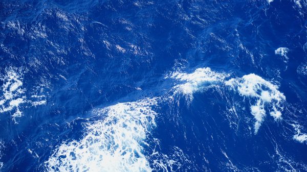 Dynamic aerial view of vibrant blue ocean waves and white surf. Nature 4K