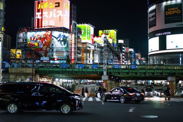 Dynamic cityscape of Shinjuku, Tokyo at night with bright neon lights and bustling streets. Voitures 4K
