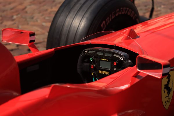 Dynamic close-up view of a red formula one racing car cockpit, showcasing the steering wheel and controls. Voitures 4K