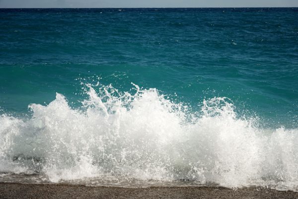 Dynamic image of a powerful ocean wave crashing on a sandy beach, capturing movement and energy. Nature 4K