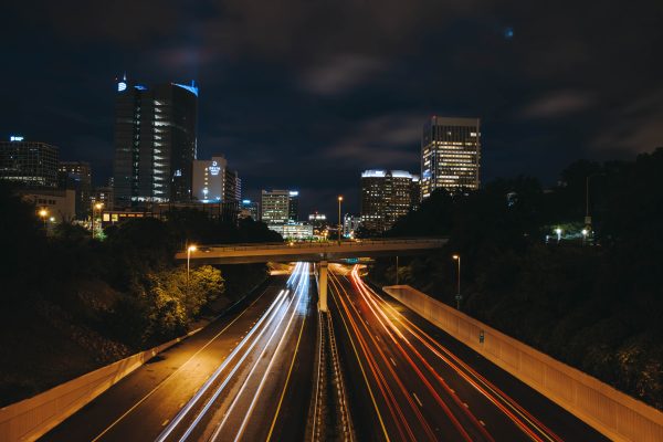 Dynamic night view of an urban highway with light trails and illuminated skyscrapers. Architecture 4K