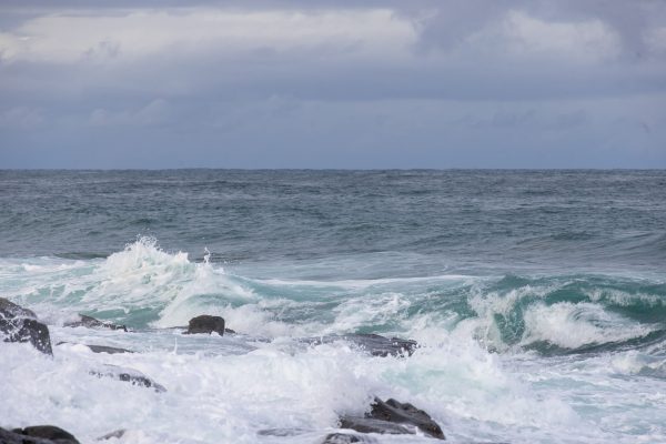Dynamic ocean waves crashing against rocky shoreline under cloudy sky. Nature 4K
