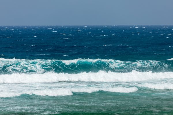 Dynamic ocean waves crashing on the shore, showcasing vibrant blue and teal hues. Nature 4K