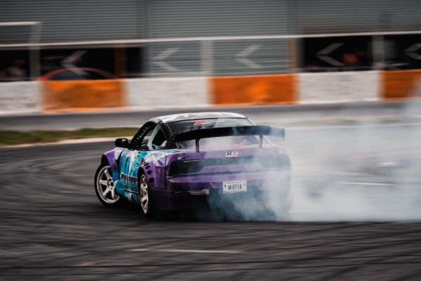 Dynamic shot of a purple sports car drifting on a race track with smoke trails. Voitures 4K