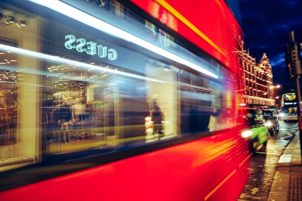 Dynamic urban night scene with a blurred red bus and illuminated streetlights showcasing city life. Voitures 4K