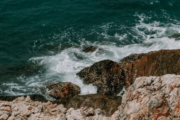 Dynamic waves crash against a rugged rocky coastline, showcasing natural beauty. Nature 4K