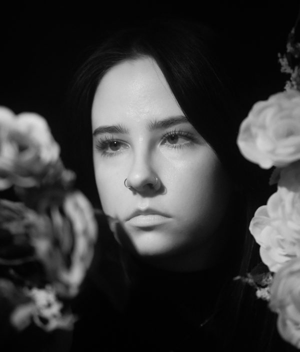 Elegant black and white portrait of a woman surrounded by flowers, evoking a serene and serious mood. Mobile 4K