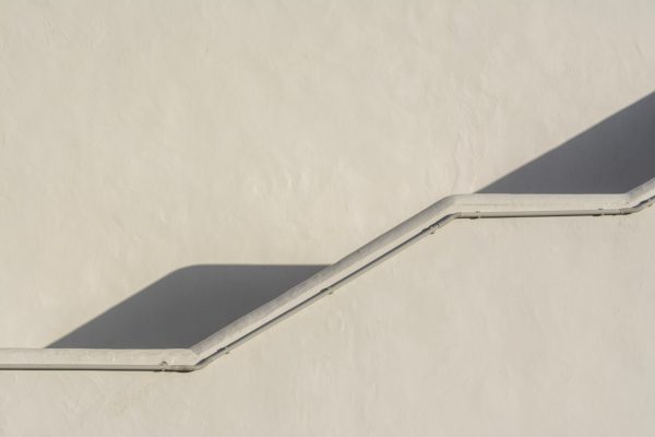 Elegant minimalist stucco wall with stairs casting geometric shadows, emphasizing simplicity. Minimaliste 4K