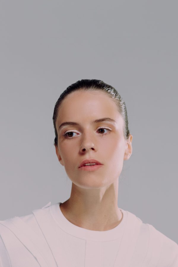Elegant portrait of a woman in white blouse, looking contemplatively to the side against a light background. Mobile 4K
