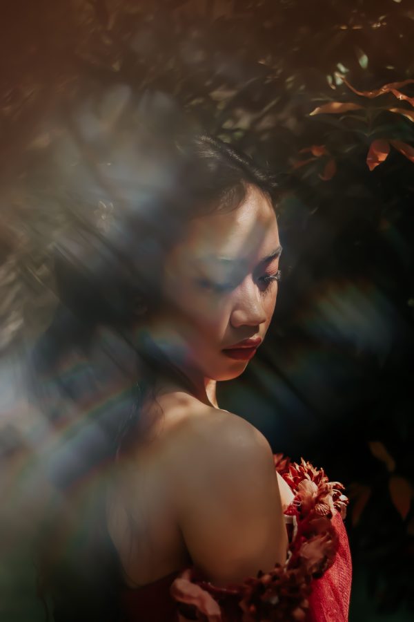 Elegant portrait of an Asian woman in a garden with dramatic lighting, wearing a red dress. Mobile 4K