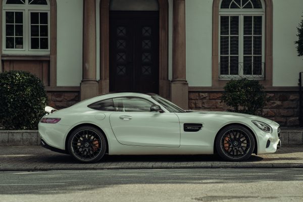 Elegant white luxury sports car parked on a street with classic architecture in the background. Voitures 4K