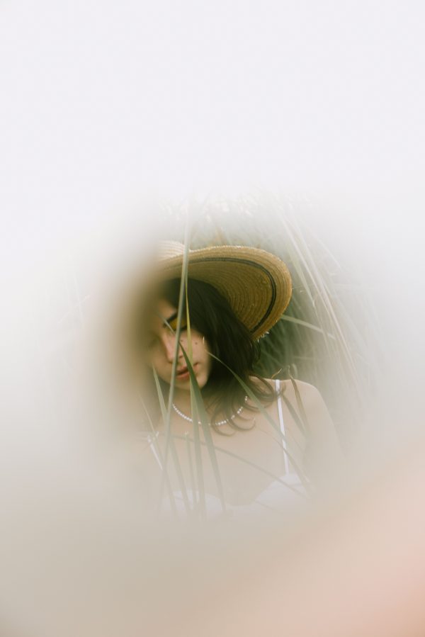 Ethereal portrait of a young woman wearing a hat, surrounded by tall grass. Mobile 4K