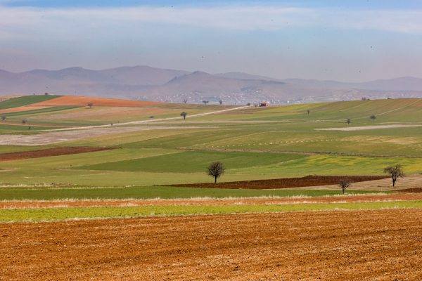 Expansive farmland with rolling hills and distant mountains under a clear sky. Nature 4K