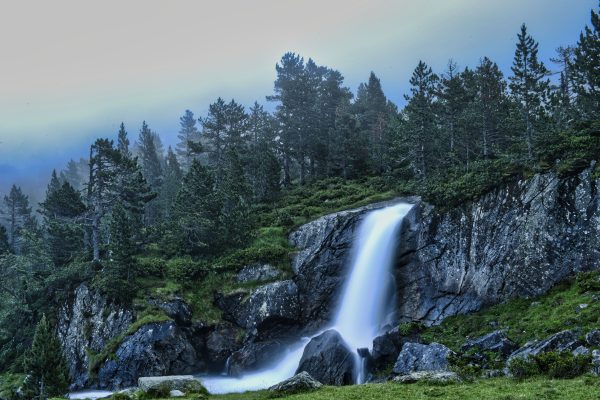 Explore the serene beauty of a cascading waterfall in Lérida, Spain, surrounded by lush greenery. Nature 4K