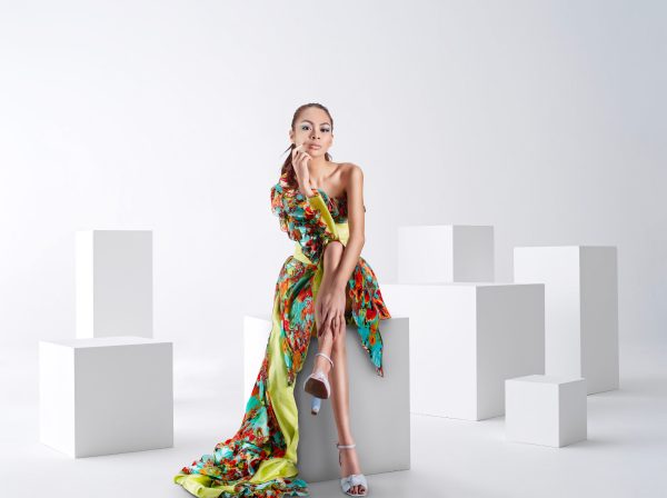 Fashionable woman in vibrant dress posing in a modern studio setting. Charme 4K