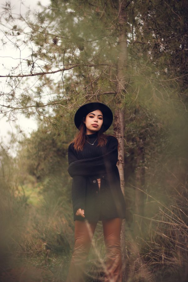 Female model in black hat posing in a forest, embracing nature's tranquility. Mobile 4K