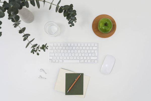 From above of modern wireless devises placed on white table among notebooks and vase with branch of eucalyptus and ripe green apple Minimaliste 4K