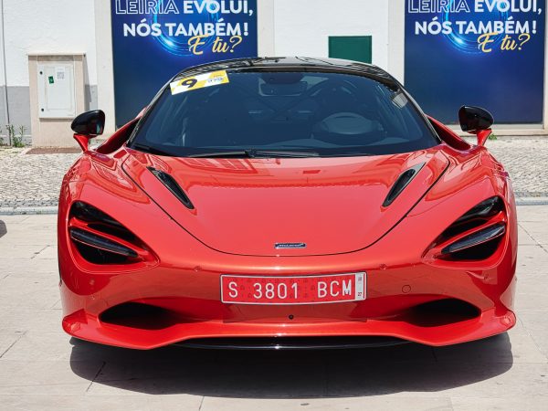 Front view of a sleek red sports car showcased in an urban area, under bright sunlight. Voitures 4K