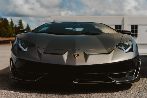 Front view of a stylish black luxury sports car parked outdoors under a clear sky. Voitures 4K