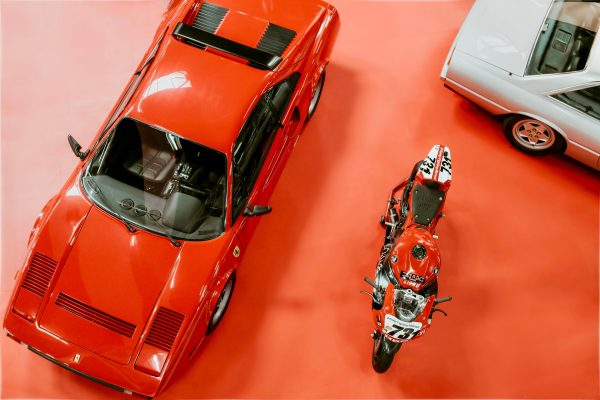High angle shot of classic Ferrari and motorcycle on display at an automotive exhibition. Voitures 4K