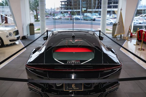 High-end black sports car displayed in a luxurious showroom with modern design elements. Voitures 4K