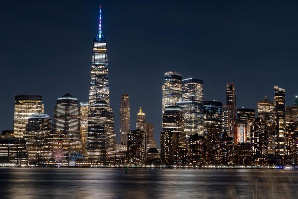 Illuminated New York City skyline featuring the iconic One World Trade Center at night. Architecture 4K