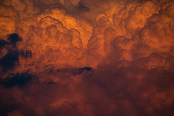 Intense orange cloud formation during sunset creating a dramatic and vivid sky scene. Dark 4K
