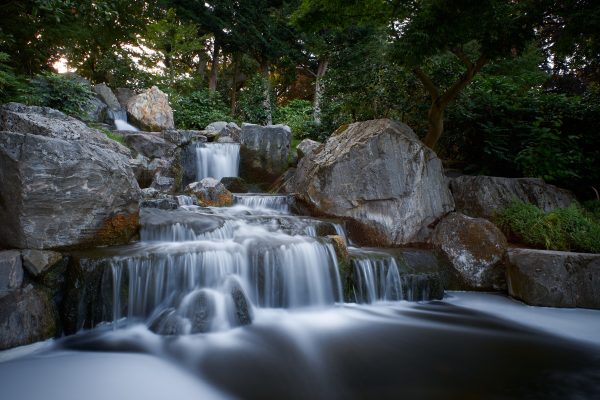 Long-exposure capture of a tranquil waterfall flowing over rocks in a peaceful forest park. Nature 4K