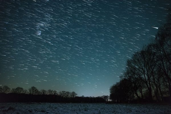 Long exposure of star trails over a snowy forest in Moisburg, Germany. Espace 4K