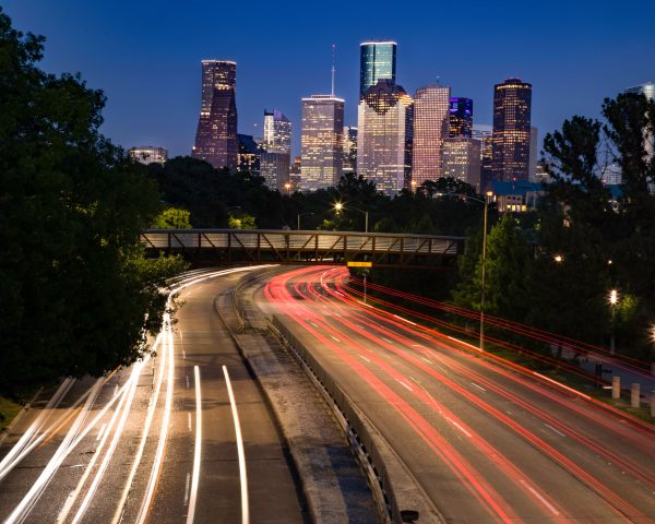 Long exposure shot of Houston's skyline at night with vibrant light trails leading into the city. Architecture 4K