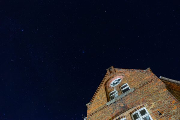 Low angle view of an old brick building against a starry night sky in Helbra, Germany. Espace 4K