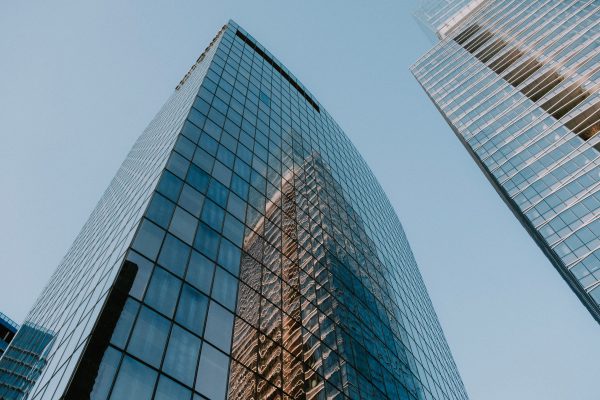 Low angle view of modern glass skyscrapers reflecting each other on a clear day. Architecture 4K