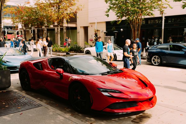 Luxurious red Ferrari parked street side with people walking by. Voitures 4K