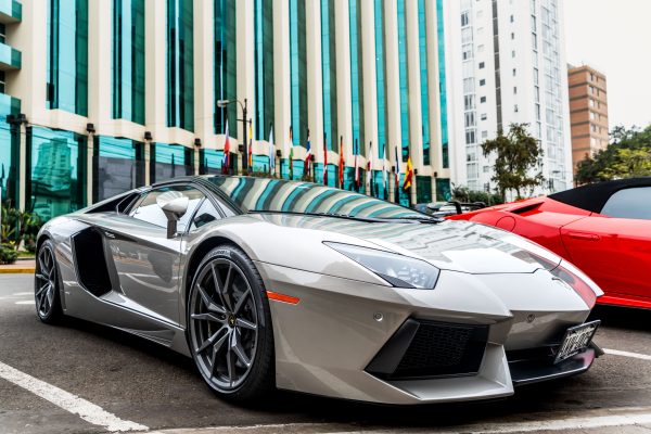 Luxury silver sports car parked in front of modern glass facade building. Voitures 4K