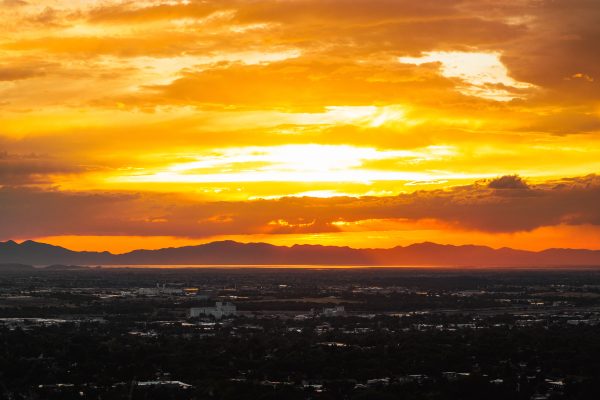 Majestic golden sunset painting the sky over an expansive cityscape with mountains in the distance. Nature 4K
