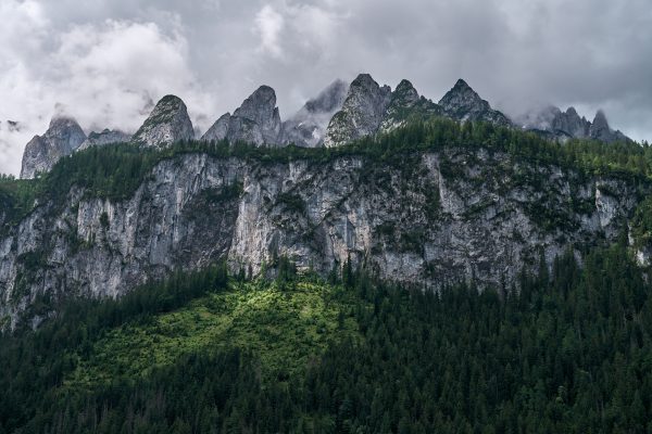 Majestic mountain range with lush forest under a cloudy sky, showcasing natural beauty and wilderness. Nature 4K