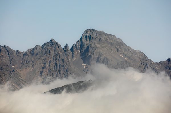 Majestic mountain range with peaks emerging through clouds on a clear day. Nature 4K