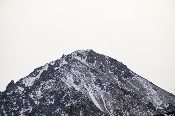 Majestic snow-covered mountain peak with rocky slopes under a clear sky. Nature 4K