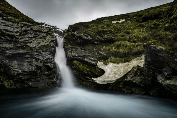 Majestic waterfall cascades through rocky terrain surrounded by greenery, creating a tranquil scene. Nature 4K