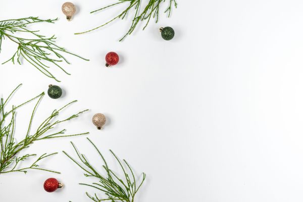 Minimalist Christmas arrangement with evergreen branches and colorful ornaments on a white background. Minimaliste 4K