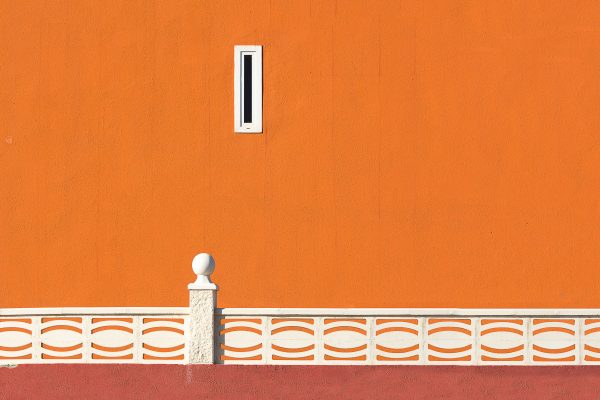Minimalist orange wall with white patterned railing and a small window in urban setting. Minimaliste 4K